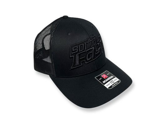 Sortafast black-on-black "Jacked Up" logo trucker hat with curved bill, shown from side angle.